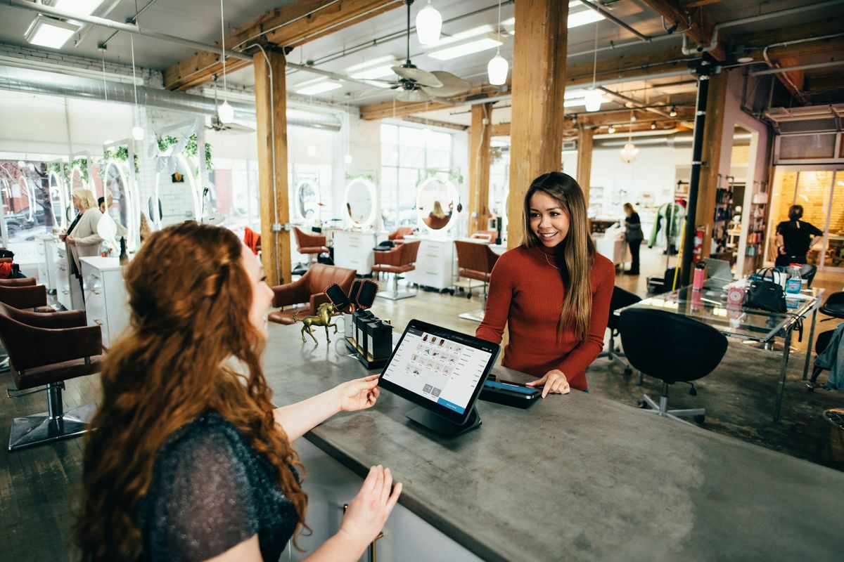 A salon owner at the front desk chatting with a client